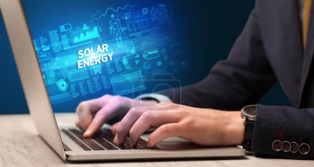 Foto de Empresario trabajando en laptop con inscripción SOLAR ENERGY, concepto de cibertecnología - Imagen libre de derechos