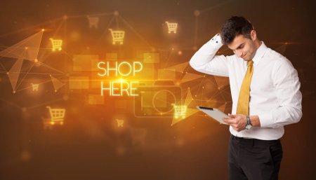 Foto de Hombre de negocios con iconos de carrito de la compra y tienda aquí inscripción, concepto de compras en línea - Imagen libre de derechos