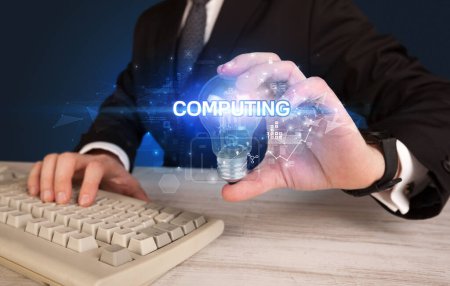 Foto de Empresario sosteniendo bombilla con inscripción COMPUTING, concepto de tecnología innovadora - Imagen libre de derechos