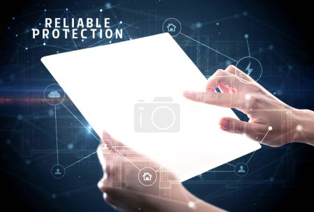 Téléchargez les photos : Tenir une tablette futuriste avec inscription PROTECTION FIABLE, concept de cybersécurité - en image libre de droit