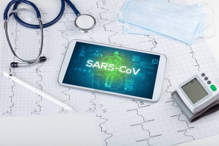 Foto de Tablet PC y herramientas médicas con inscripción SARS-CoV, concepto de coronavirus - Imagen libre de derechos