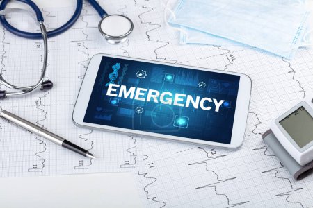 Téléchargez les photos : Tablette pc et matériel médical avec inscription d'urgence, concept de prévention - en image libre de droit