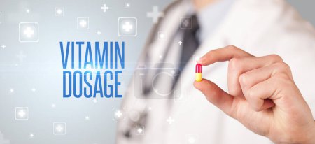 Photo for Close-up of a doctor giving a pill with VITAMIN DOSAGE inscription, medical concept - Royalty Free Image