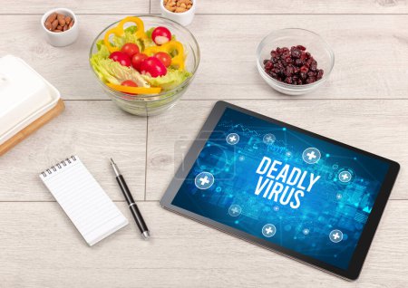 Téléchargez les photos : Concept DEADLY VIRUS en comprimé PC avec des aliments sains autour, vue du dessus - en image libre de droit
