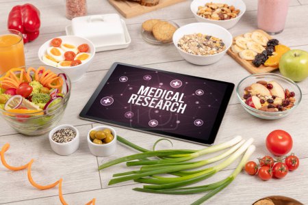 Téléchargez les photos : RECHERCHE MÉDICALE concept en tablette PC avec des aliments sains autour, vue du dessus - en image libre de droit