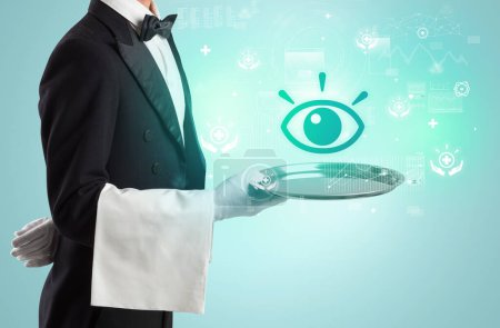 Photo for Handsome young waiter in tuxedo holding tray with eye icons on tray, global healthcare concept - Royalty Free Image
