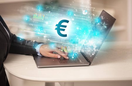 Téléchargez les photos : Jeune homme regardant le marché boursier sur ordinateur portable avec des icônes euro, concept de forex - en image libre de droit