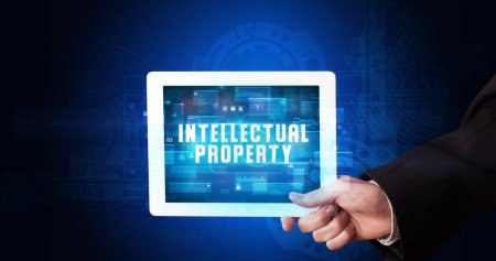 Photo for Young business person working on tablet and shows the digital sign: INTELLECTUAL PROPERTY - Royalty Free Image
