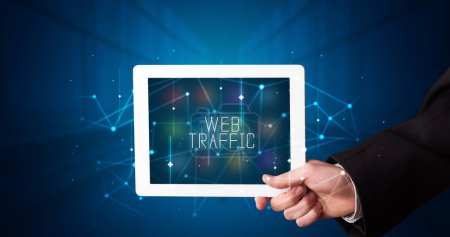 Photo for Young business person working on tablet and shows the digital sign: WEB TRAFFIC - Royalty Free Image