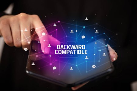 Foto de Empresario sosteniendo un smartphone plegable con inscripción COMPATIBLE BACKWARD, concepto de nueva tecnología - Imagen libre de derechos
