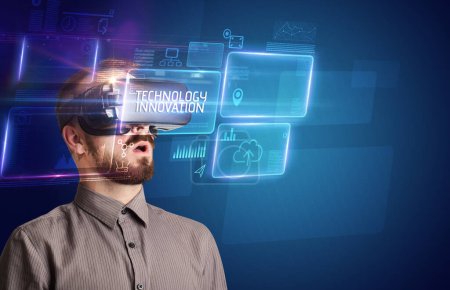 Téléchargez les photos : Homme d'affaires regardant à travers des lunettes de réalité virtuelle avec inscription TECHNOLOGY INNOVATION, nouveau concept technologique - en image libre de droit
