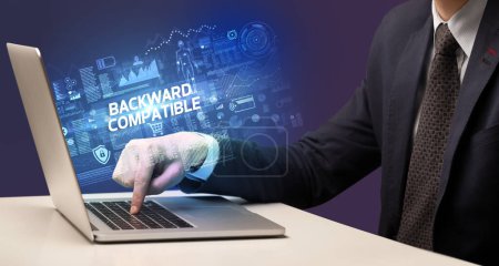 Foto de Empresario trabajando en laptop con inscripción COMPATIBLE BACKWARD, concepto de cibertecnología - Imagen libre de derechos