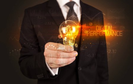 Téléchargez les photos : Homme d'affaires tenant une ampoule avec inscription DIGITAL PERFORMANCE, concept de technologie d'entreprise - en image libre de droit