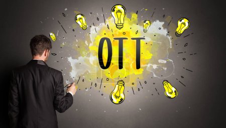 Téléchargez les photos : Homme d'affaires dessin ampoule colorée avec abréviation OTT, concept idée nouvelle technologie - en image libre de droit