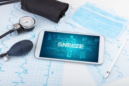 Foto de Tablet PC y herramientas médicas con inscripción SNEEZE, concepto de coronavirus - Imagen libre de derechos