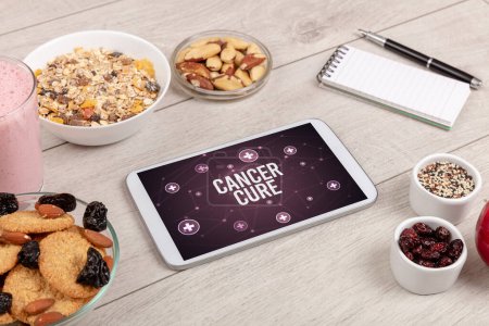Téléchargez les photos : CANCER CURE concept en comprimé PC avec des aliments sains autour, vue du dessus - en image libre de droit