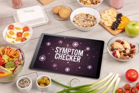 Foto de Concepto SYMPTOM CHECKER en PC tableta con alimentos saludables alrededor, vista superior - Imagen libre de derechos