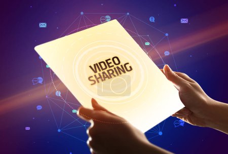 Téléchargez les photos : Tenir une tablette futuriste avec inscription VIDEO SHARING, concept de médias sociaux - en image libre de droit