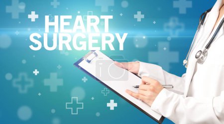 Photo for Doctor writes notes on the clipboard with HEART SURGERY inscription, first aid concept - Royalty Free Image