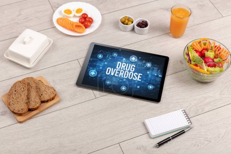 Foto de DROGAS concepto de sobredosis en la tableta PC con alimentos saludables alrededor, vista superior - Imagen libre de derechos