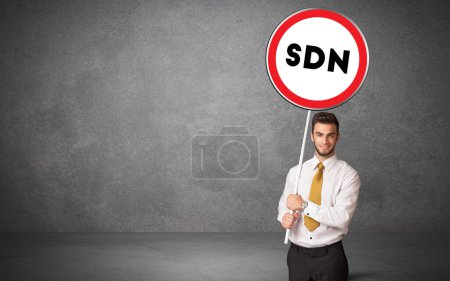 Téléchargez les photos : Jeune homme d'affaires holdig panneau de signalisation avec abréviation SDN, concept de solution technologique - en image libre de droit