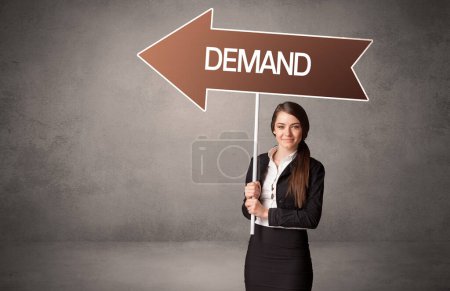 Photo for Young business person in casual holding road sign with DEMAND inscription, business direction concept - Royalty Free Image