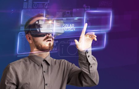 Téléchargez les photos : Homme d'affaires regardant à travers des lunettes de réalité virtuelle avec inscription SOLAR ENERGY, nouveau concept technologique - en image libre de droit