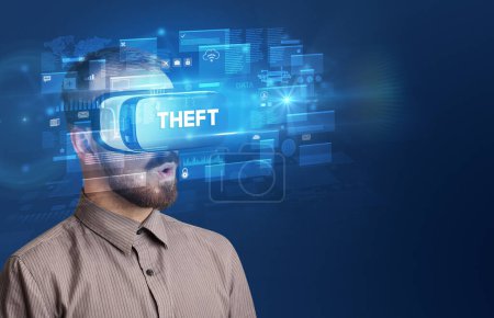 Téléchargez les photos : Homme d'affaires regardant à travers des lunettes de réalité virtuelle avec l'inscription THEFT, concept de sécurité innovant - en image libre de droit
