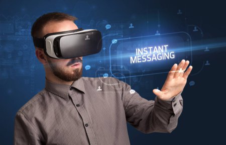 Foto de Hombre de negocios mirando a través de gafas de realidad virtual con inscripción INSTANT MESSAGING, concepto de redes sociales - Imagen libre de derechos