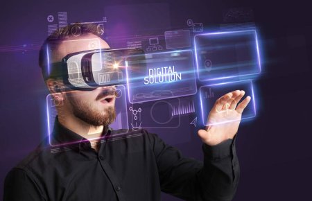 Téléchargez les photos : Homme d'affaires regardant à travers des lunettes de réalité virtuelle avec inscription DIGITAL SOLUTION, concept de nouvelle technologie - en image libre de droit