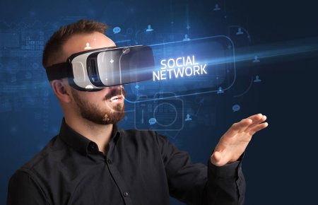 Téléchargez les photos : Homme d'affaires regardant à travers des lunettes de réalité virtuelle avec inscription RÉSEAU SOCIAL, concept de réseautage social - en image libre de droit