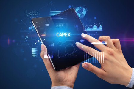 Téléchargez les photos : Homme d'affaires tenant un smartphone pliable avec inscription CAPEX, concept d'entreprise réussi - en image libre de droit