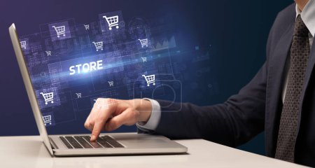 Foto de Empresario que trabaja en el ordenador portátil con inscripción STORE, concepto de compras en línea - Imagen libre de derechos