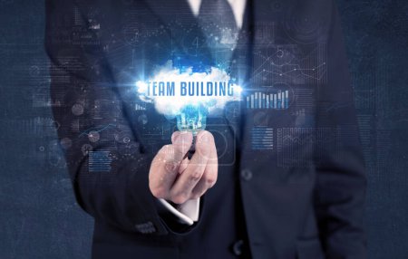 Foto de Empresario sosteniendo una bombilla con inscripción TEAM BUILDING, nuevo concepto de negocio - Imagen libre de derechos