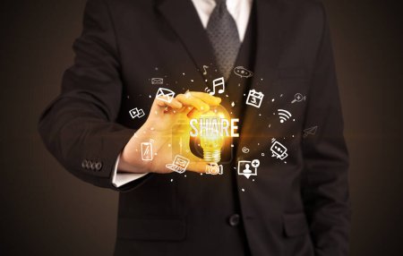 Foto de Empresario sosteniendo bombilla con inscripción SHARE, concepto de redes sociales - Imagen libre de derechos