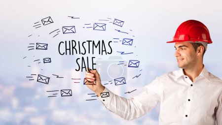 Photo for Handsome businessman with helmet drawing CHRISTMAS SALE inscription, contruction sale concept - Royalty Free Image