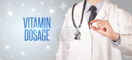 Photo for Close-up of a doctor giving a pill with VITAMIN DOSAGE inscription, medical concept - Royalty Free Image