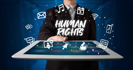 Téléchargez les photos : Jeune homme d'affaires travaillant sur tablette et montre l'inscription : DROITS DE L'HOMME - en image libre de droit