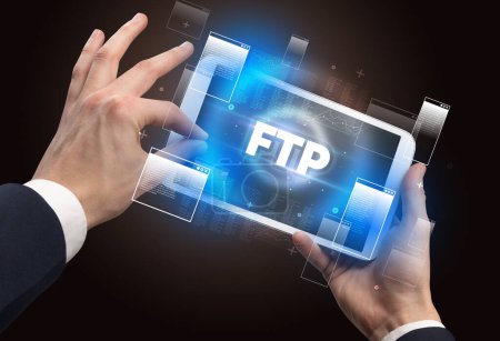 Photo for Close-up of a hand holding tablet with FTP abbreviation, modern technology concept - Royalty Free Image