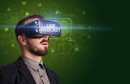 Téléchargez les photos : Homme d'affaires regardant à travers des lunettes de réalité virtuelle avec inscription LIVE WEBCAST, concept de réseautage social - en image libre de droit