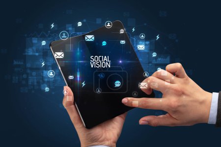 Foto de Empresario sosteniendo un smartphone plegable con inscripción SOCIAL VISION, concepto de redes sociales - Imagen libre de derechos