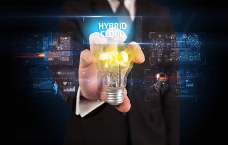 Foto de Empresario sosteniendo bombilla con inscripción HYBRID CLOUD, concepto de idea de seguridad en línea - Imagen libre de derechos