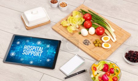 Téléchargez les photos : HOSPITAL SUPPORT concept en comprimé PC avec des aliments sains autour, vue du dessus - en image libre de droit