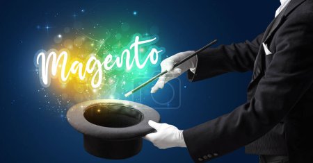 Téléchargez les photos : Main de magicien évoquer avec baguette et inscription Magento, concept shopping - en image libre de droit