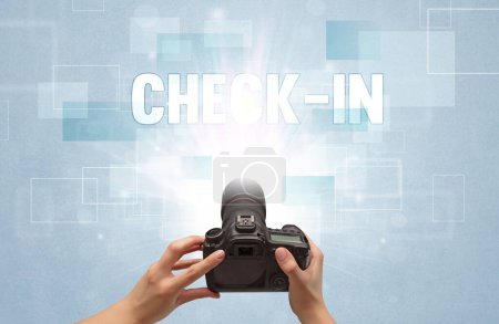 Téléchargez les photos : Gros plan d'un appareil photo numérique à main avec inscription CHECK-IN, concept itinérant - en image libre de droit