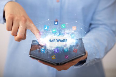 Foto de Empresario sosteniendo un smartphone plegable con inscripción HARDWARE, concepto de tecnología - Imagen libre de derechos