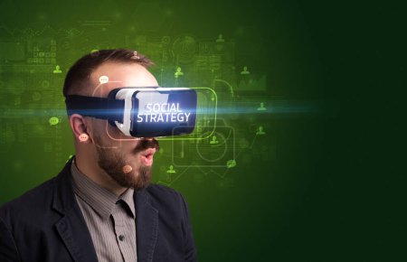Téléchargez les photos : Homme d'affaires regardant à travers des lunettes de réalité virtuelle avec inscription STRATÉGIE SOCIALE, concept de réseautage social - en image libre de droit