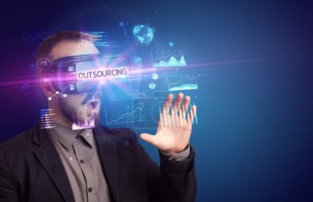 Foto de Hombre de negocios mirando a través de gafas de realidad virtual con inscripción OUTSOURCING, nuevo concepto de negocio - Imagen libre de derechos