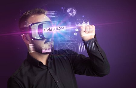 Foto de Hombre de negocios mirando a través de gafas de realidad virtual con inscripción TEAM BUILDING, nuevo concepto de negocio - Imagen libre de derechos
