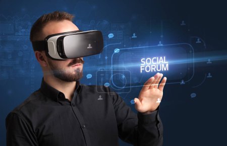 Téléchargez les photos : Homme d'affaires regardant à travers des lunettes de réalité virtuelle avec inscription FORUM SOCIAL, concept de réseautage social - en image libre de droit